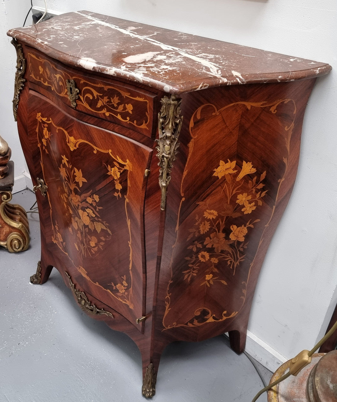 Stunning French Transitional style Mahogany marquetry inlay salon cabinet in the bombe shape. It has one draw, one shelf, marble top & ormolu decoration. Sourced from France and in good original detailed condition.