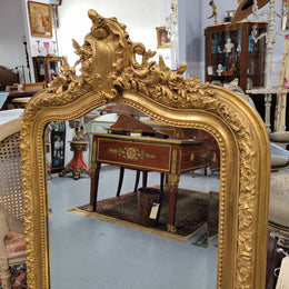 Beautiful French Napoleon III Louis XV style gilt framed bevelled mirror with an ornate crest on top. It has been sourced from France and is in good original detailed condition with the mirror showing signs of age.