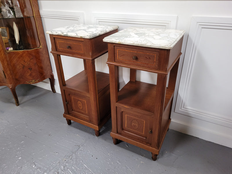 Pair of Antique French Oak Louis XVI style marble top bedside cabinets. They have decorative inlay and have been sourced from France. They are in good original detailed condition.