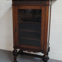 A very practical compact Oak Tudor style display cabinet with three fixed shelves. In good original detailed condition.