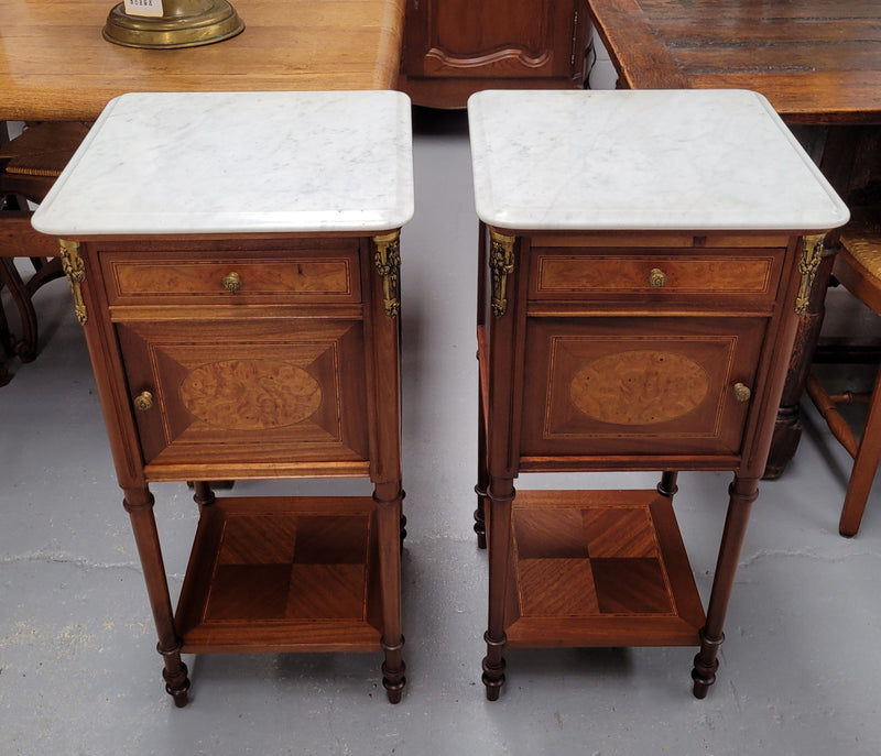 Pair of white marble topped Louis 16th style bedside cabinets consisting of one drawer and one cupboard.  Inlaid with burr walnut and has decorative mounts. They have been sourced from France and are in good original condition.