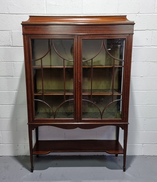 Edwardian Sheraton Revival Mahogany display cabinet with green upholstered  fabric backing and shelving with inlay and two decorative glazed doors.