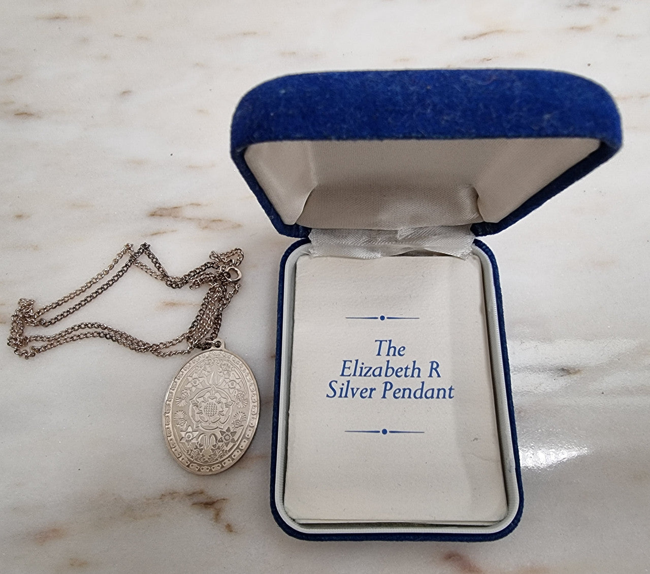 Attractive oval-shaped sterling silver ingot pendant issued by Franklin Mint in 1977 to commemorate Queen Elizabeth II Silver Jubilee. It comes with its original box and paperwork.