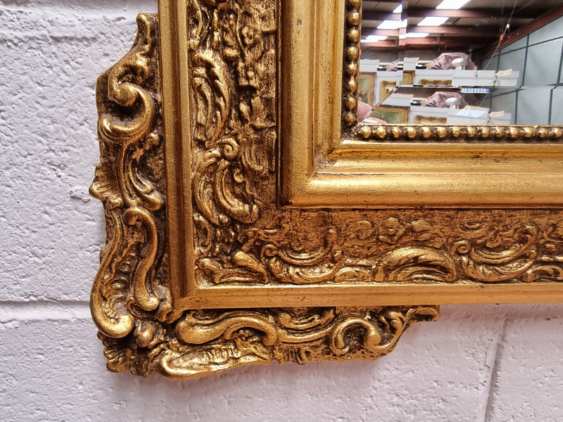 French ornate gilt framed wall mirror with bevelled mirror and decorated with water dragons. This has been sourced from France and is in good original condition.