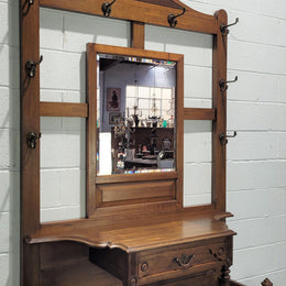 Impressive Oak hall stand of grand portions. Plenty of storage with a drawer, plenty of hooks and two sections for umbrealls/ walking sticks. It is in good original detailed condition.