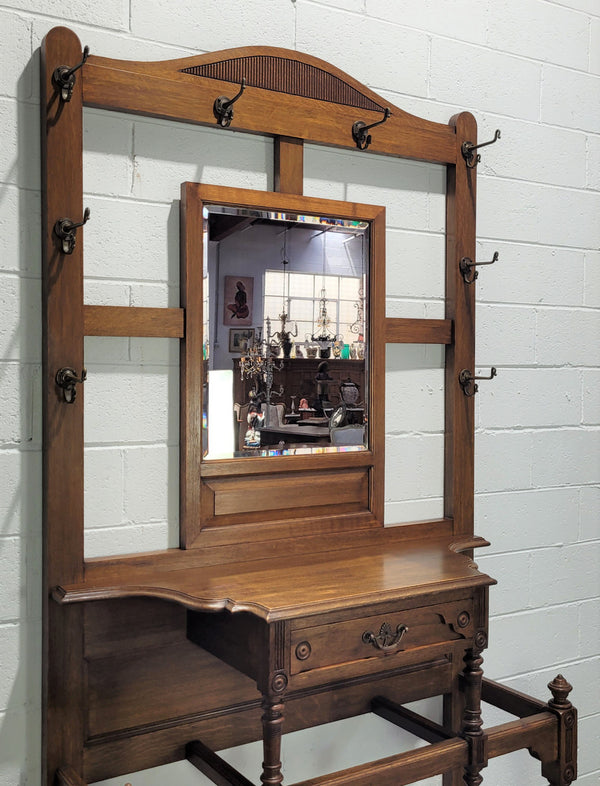 Impressive Oak hall stand of grand portions. Plenty of storage with a drawer, plenty of hooks and two sections for umbrealls/ walking sticks. It is in good original detailed condition.