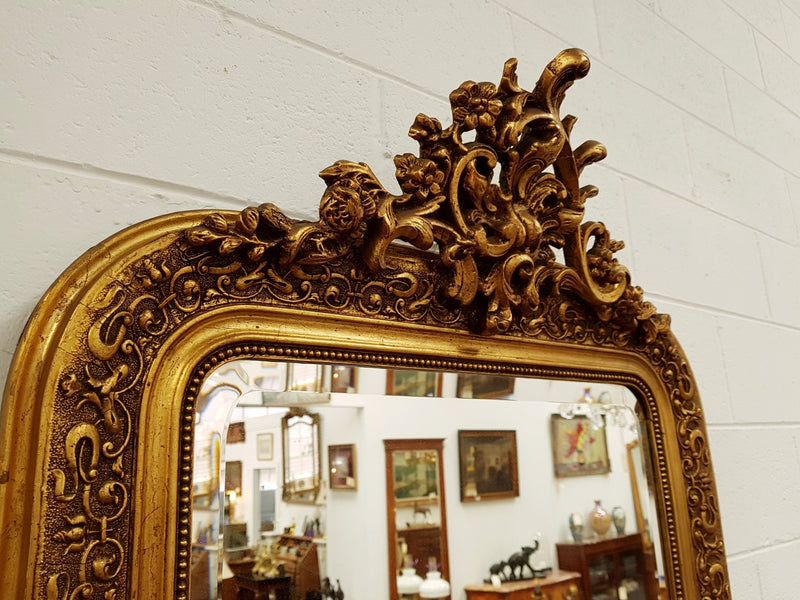 19th Century French Louis XV style gilt wall mirror with fabulous highly decorative crest at the top and a beveled edge mirror. In good original detailed condition.