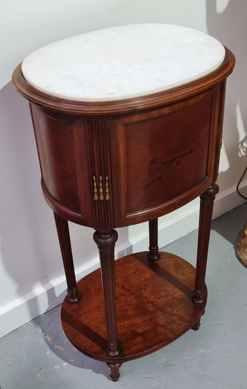 Round Louis XVI style Mahogany marble top side table. It has one drawer and a cupboard for storage. It is in good original detailed condition.