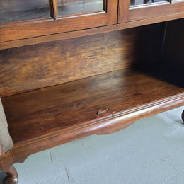 English Walnut two door bookcase with original glass. It has three adjustable shelves and hidden storage below behind two smaller doors. It is in food original condition.