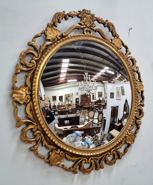 Large round convex mirror in a decorative carved wood gilt frame. In good original detailed condition.