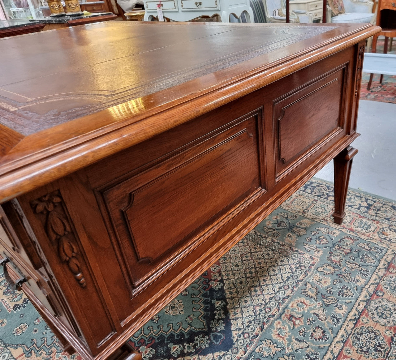 Substantial French Louis XVI style Oak partners desk. It has a beautiful leather top, two drawers on either side and decorative carvings throughout. Sourced from France and in good original detailed condition.