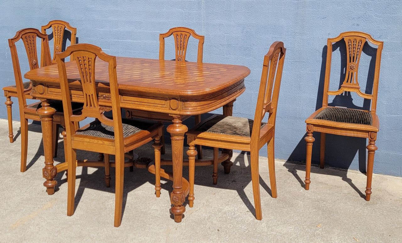 Beautiful carved French Oak dining table with a parquetry top and six matching upholstered chairs. All in good original detailed condition.