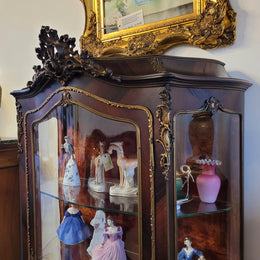 French Louis XV style marquetry inlaid vitrine with ormolu mounts and curved glass. The inside in lined with a red velvet upholstery and has two glass shelves. It has been sourced from France and is in good original detailed condition.