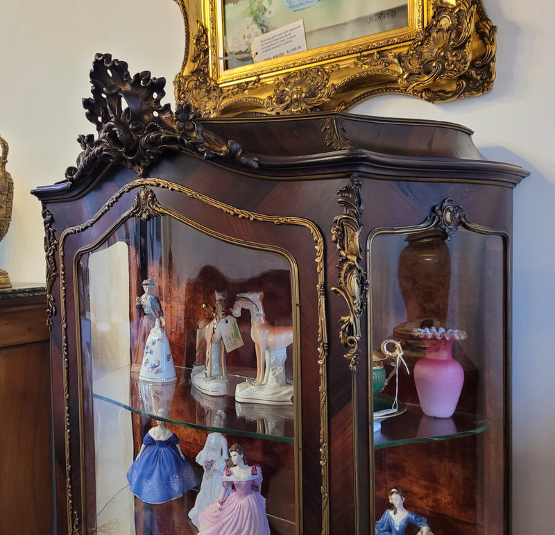 French Louis XV style marquetry inlaid vitrine with ormolu mounts and curved glass. The inside in lined with a red velvet upholstery and has two glass shelves. It has been sourced from France and is in good original detailed condition.