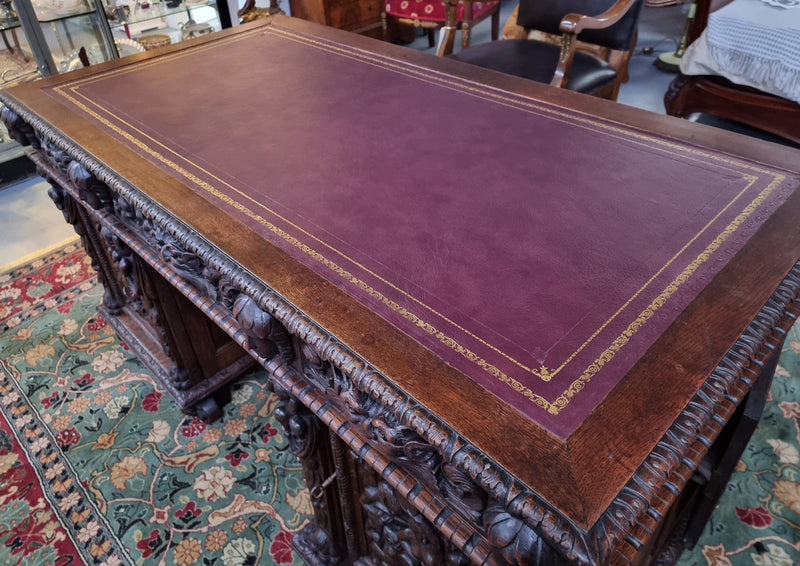 Beautifully carved French Oak early 19th century pedestal desk with 3 drawers, two cupboards and a secret cupboard on the side. There is also a lovely burgundy tooled leather top. In good original detailed condition.