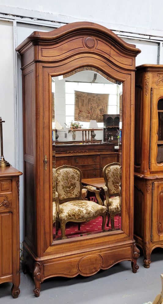 French Louis XV style Walnut armoire with single bevelled mirrored door. It has four adjustable shelves and a hidden exterior drawer at the bottom. It has been sourced from France and is in good original detailed condition.