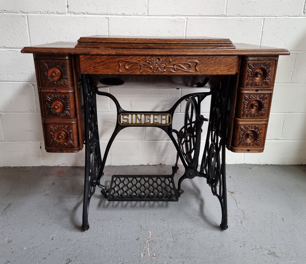 Singer Treadle sewing machine with six decorative side drawers and one centre drawer in Oak on cast iron base. It is in original condition.