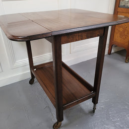 Oak drop leaf auto trolley on wheels. Both sides open up to make a larger table. It is in good original detailed condition.