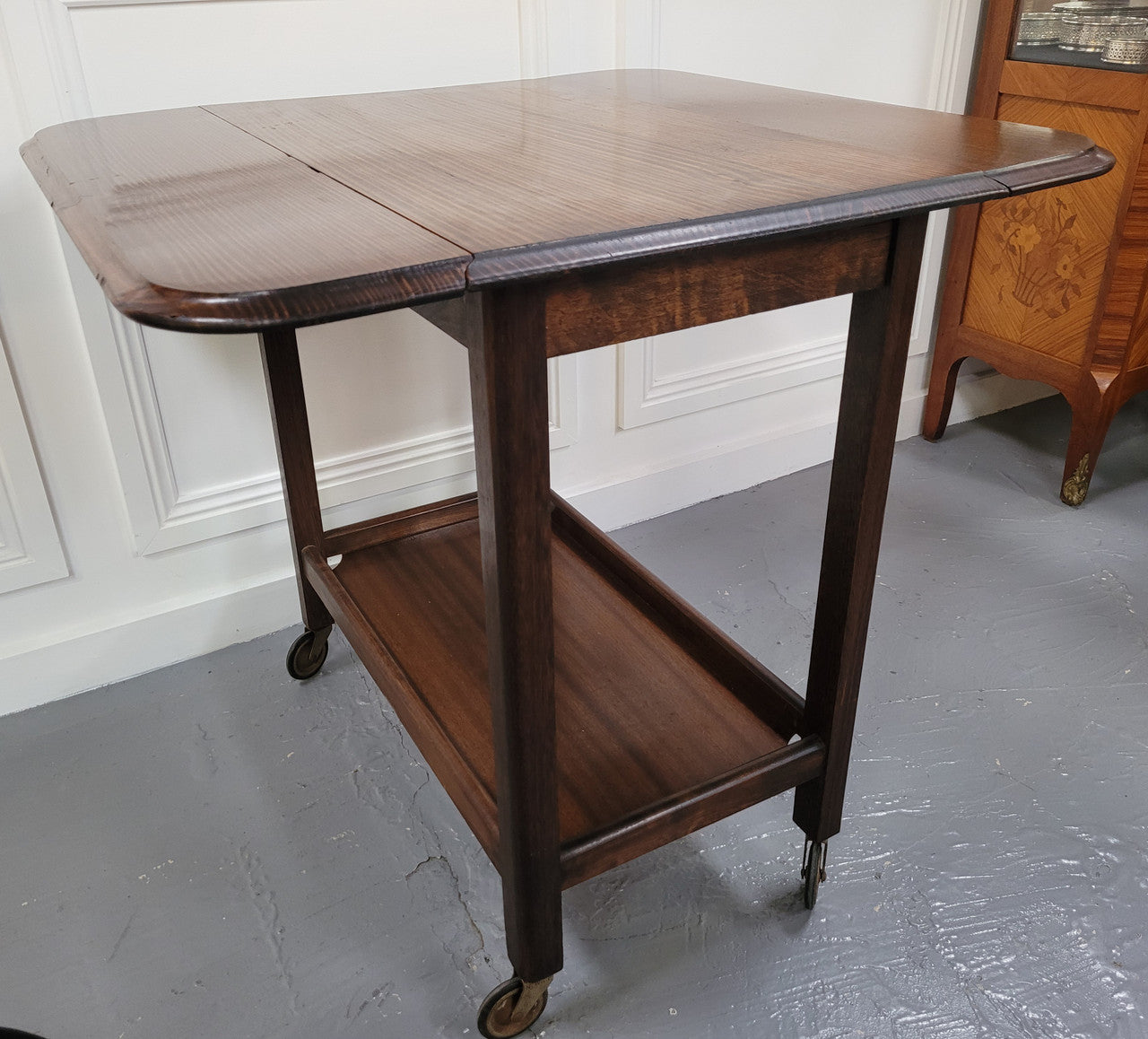 Oak drop leaf auto trolley on wheels. Both sides open up to make a larger table. It is in good original detailed condition.
