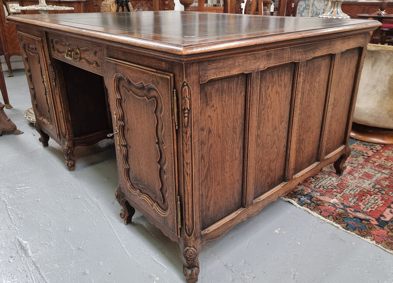 Fabulous Louis XV style French Oak beautifully carved full partners desk with an amazing tooled leather top. Both sides have a functioning drawer in the middle and two cupboards either side. On both sides one cupboard door opens up to four smaller internal drawers. Plenty of storage space and a large top surface to work on. It is in good original detailed condition.
