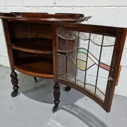 Oak Tudor auto trolley with beautiful leadlight glass. It is on wheels and the door open up to a cabinet with one shelf. In good original detailed condition.