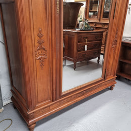 Imposing Louis XV style single mirrored door Walnut armoire. Features deep carved decoration, two interior drawers and three adjustable shelves. It is in good original detailed condition and has been sourced from France.