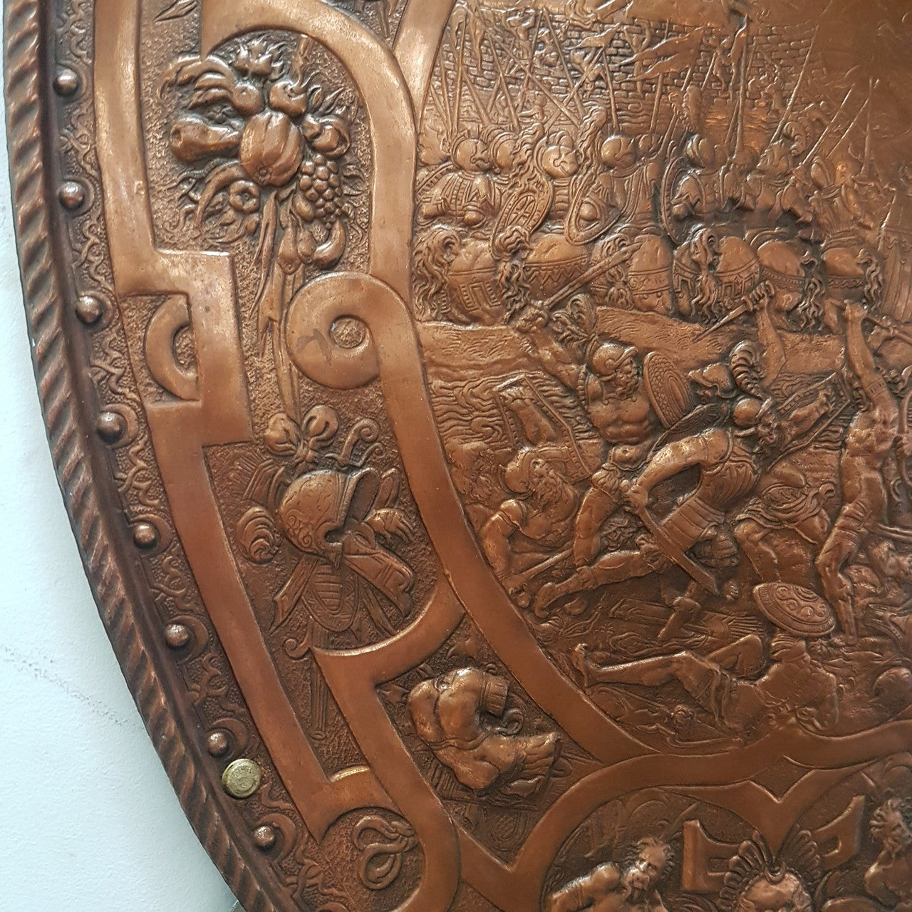 A beautiful European Antique highly detailed embossed copper shield with swords. Look closely to see the amazing detail in the shield of a fighting scene. It has brass handles on the steel swords. Is in good original condition with a slight crack (see photo).