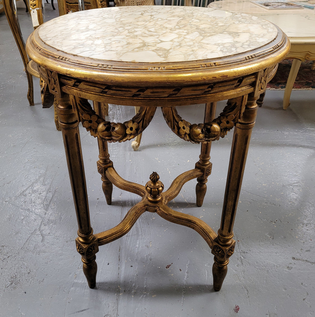 French Louis XVI style round marble topped gilded lamp/side table featuring lovely carved swags and undercarriage. It has been sourced from France and is in good original detailed condition.