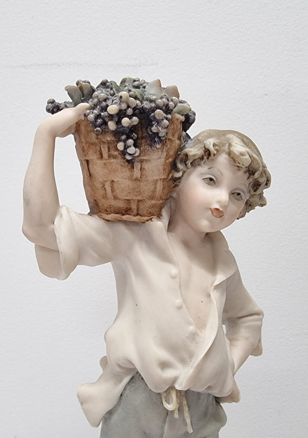 Lovely Italian figurine of boy carrying basket with grapes on a wooden base. It is signed Giuseppe Armani and 1982 FLORENCE. In good original condition.  Please view photos as they form part of the description.