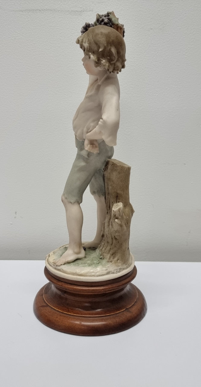 Lovely Italian figurine of boy carrying basket with grapes on a wooden base. It is signed Giuseppe Armani and 1982 FLORENCE. In good original condition.  Please view photos as they form part of the description.