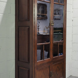 English Walnut two door bookcase with original glass. It has three adjustable shelves and hidden storage below behind two smaller doors. It is in food original condition.