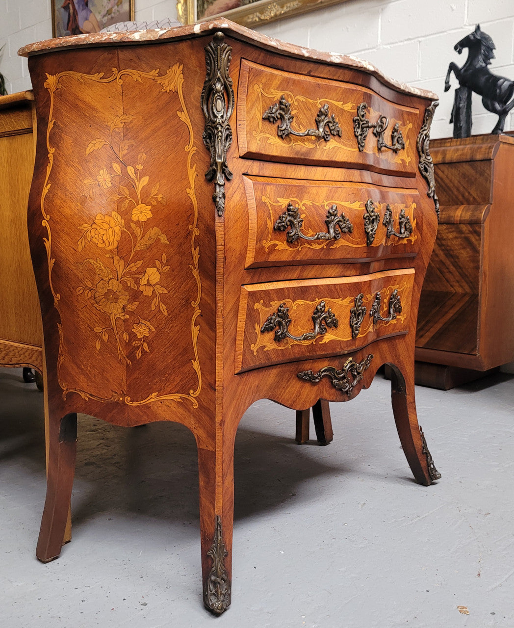 Antique French Louis XV style compact three drawer marble top commode with marquetry inlay and ormolu mounts. Sourced from France and in good original detailed condition.