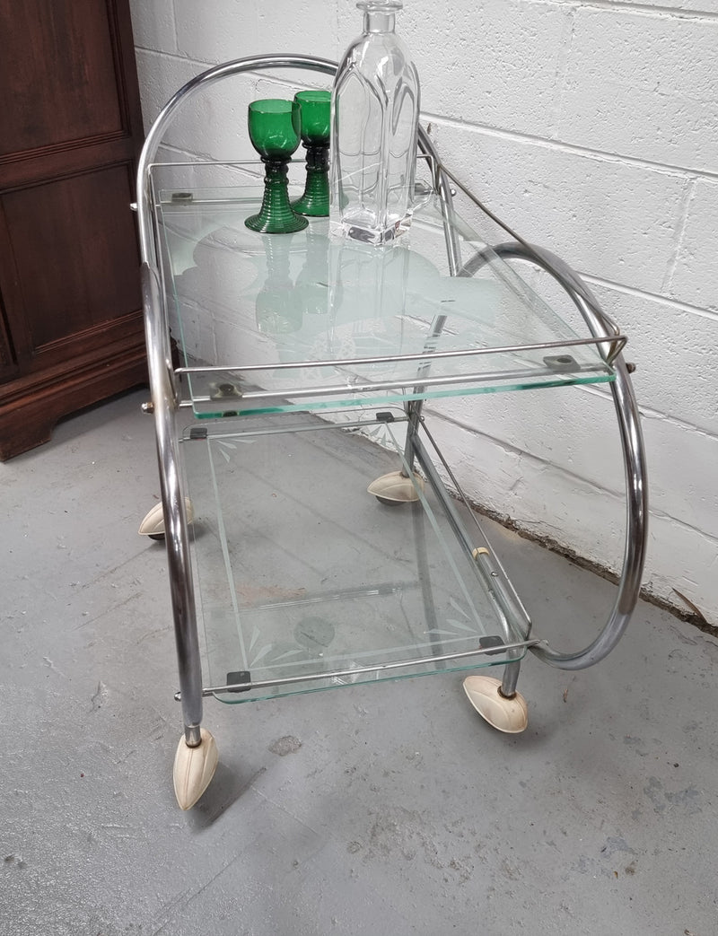 Stylish Art Deco chrome & frosted glass drinks trolley. Bakelite guards on the wheels. It is in good original condition and has been sourced locally.