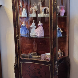 French Louis XV style marquetry inlaid vitrine with ormolu mounts and curved glass. The inside in lined with a red velvet upholstery and has two glass shelves. It has been sourced from France and is in good original detailed condition.