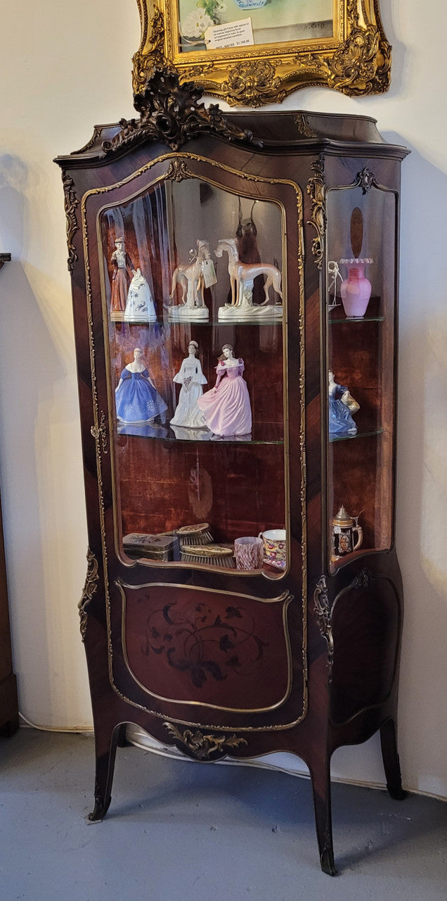French Louis XV style marquetry inlaid vitrine with ormolu mounts and curved glass. The inside in lined with a red velvet upholstery and has two glass shelves. It has been sourced from France and is in good original detailed condition.