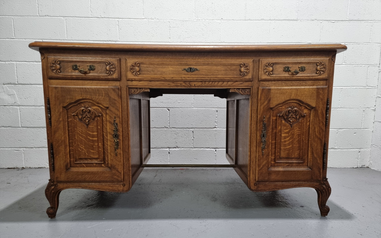 Fabulous French oak carved partners desk with a lovely parquetry top. It has three drawers and two cupboards on one side and two cupboards on the other side with no functioning drawers. It is in good original detailed condition.