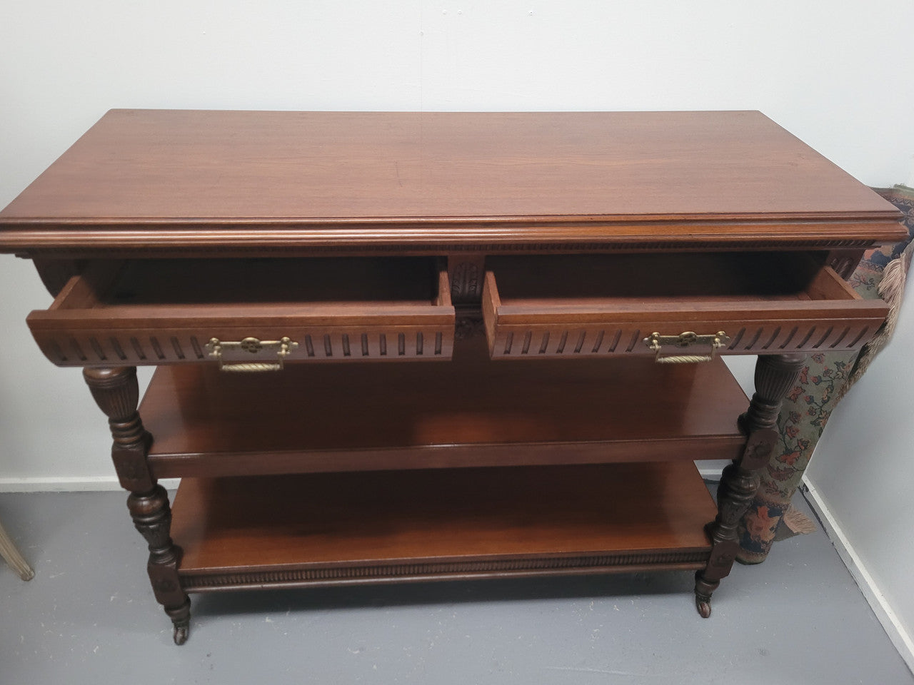 Fabulous quality Edwardian Walnut dumb waiter. It has two drawers and two shelves and is on casters. In good original detailed condition.