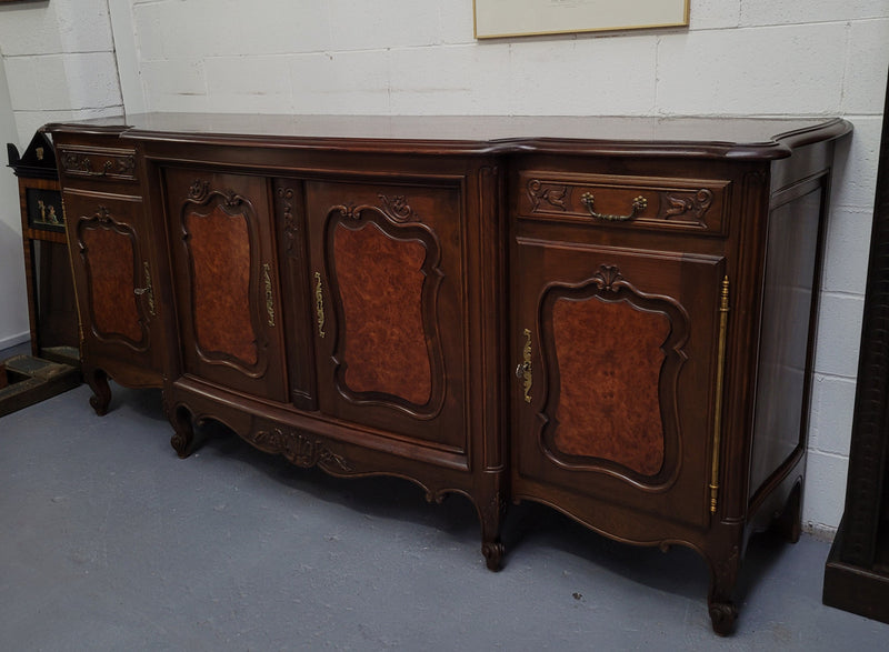 Fabulous Louis XV style French Walnut and Burr Walnut four door sideboard. Each door panel has beautiful Burr Walnut panels and open up to an adjustable shelf. Beautiful handles and two drawers for added storage. In good original detailed condition.