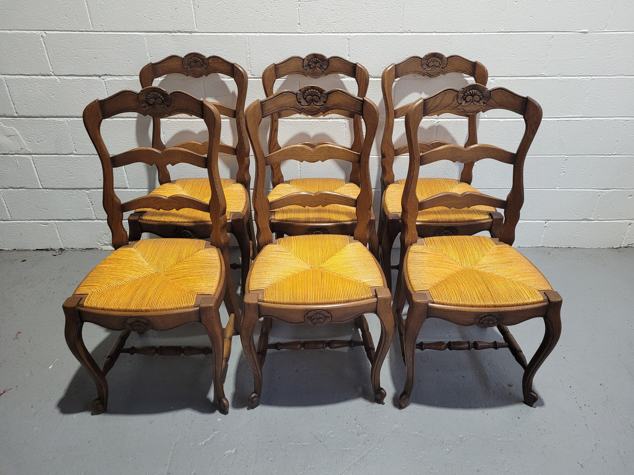 A set of 6 French Louis XV style oak dining chairs with rush seats in good original condition. All chairs have been detailed and re-glued where needed.