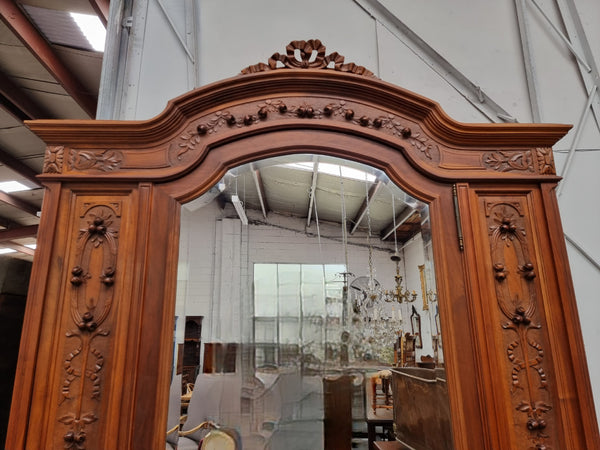 Imposing Louis XV style single mirrored door Walnut armoire. Features deep carved decoration, two interior drawers and three adjustable shelves. It is in good original detailed condition and has been sourced from France.