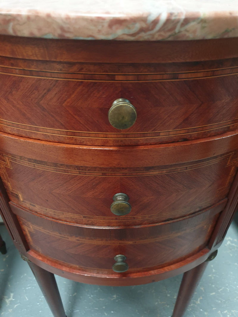 Rare pair of oval Louis XVI style inlaid bedside drawers, with beautiful marble tops. They are in very good restored condition. Circa 1920's.