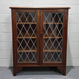 Lovely leadlight two door Oak bookcase/display cabinet with four wooden shelves. It is in good original detailed condition.