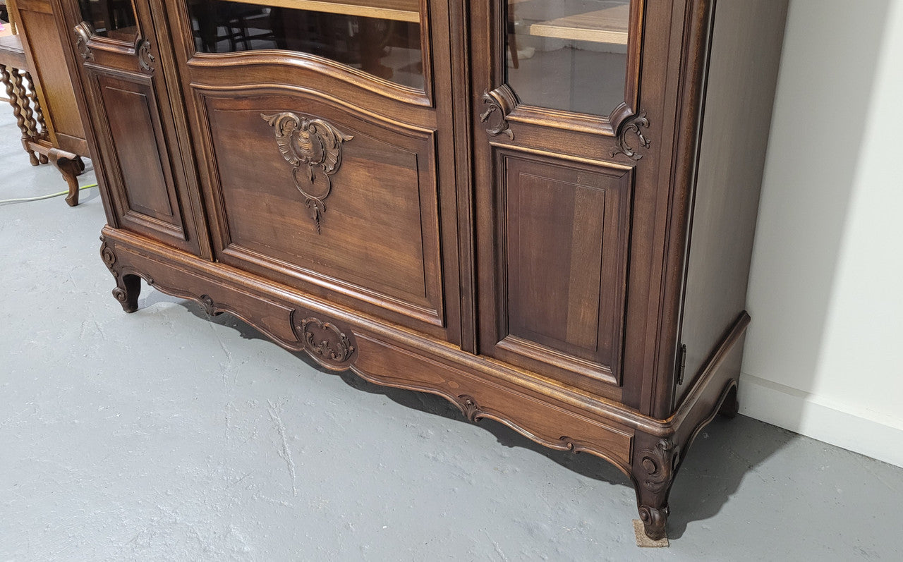 French Louis XV style walnut three door bookcase. It has adjustable shelves and is in good original detailed condition.