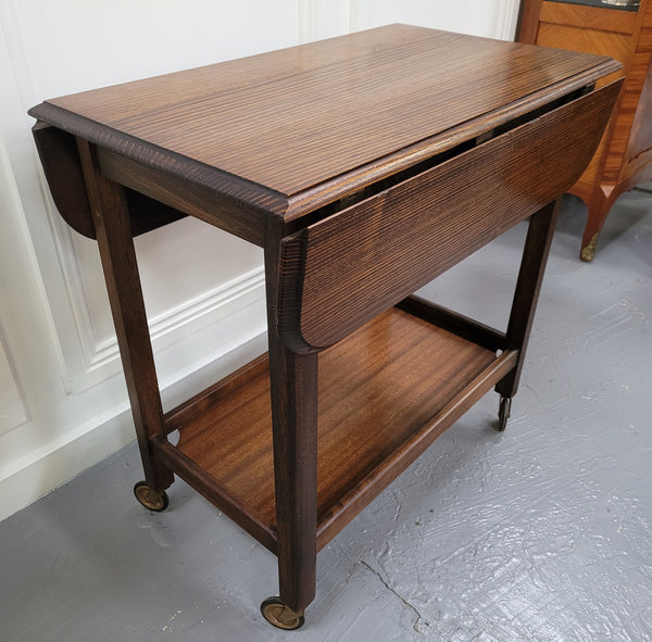 Oak drop leaf auto trolley on wheels. Both sides open up to make a larger table. It is in good original detailed condition.