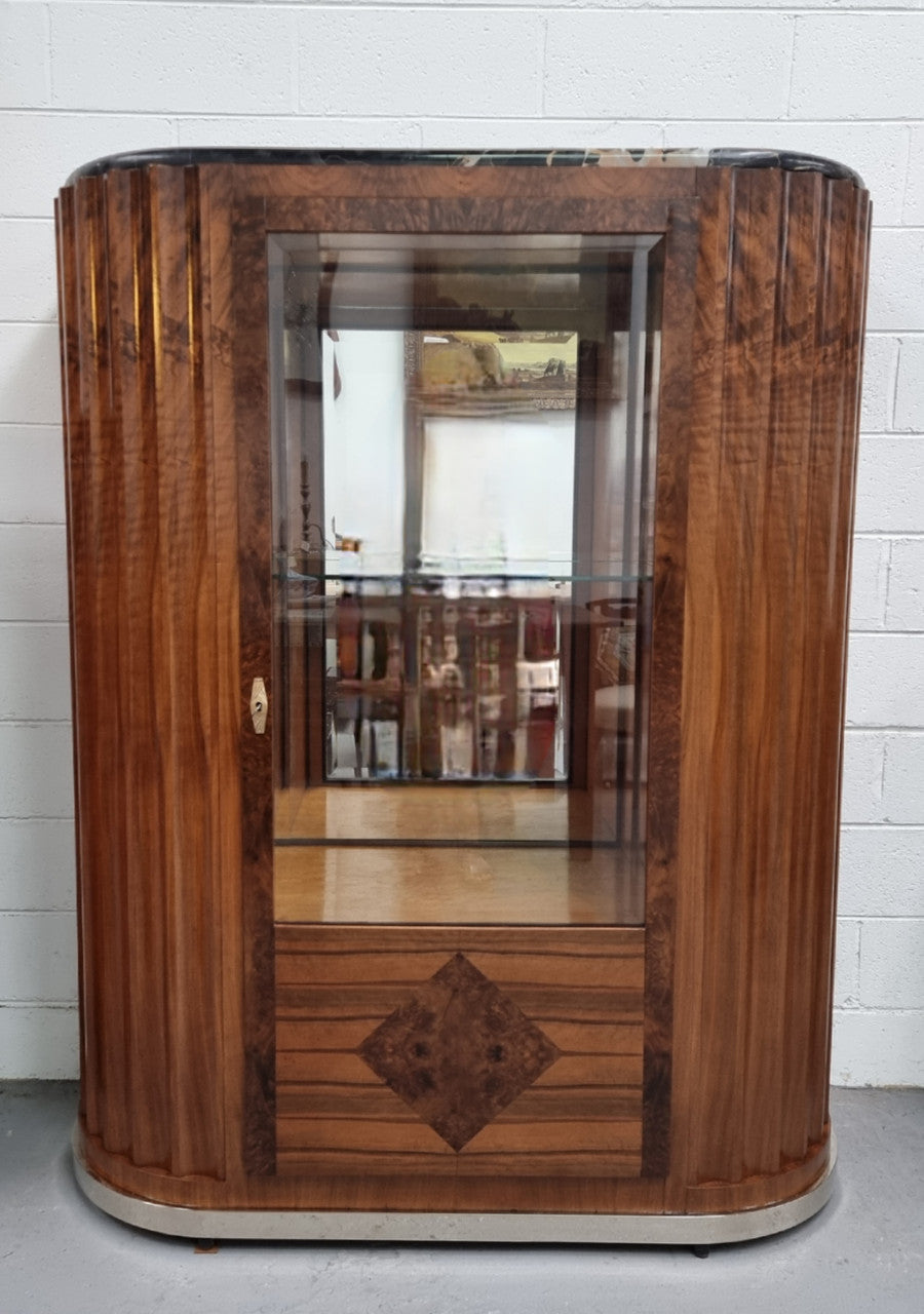 Stunning French Art Deco figured Walnut with Portoro marble top cocktail cabinet. Features chrome trim on base and glass display in door. It is in fully restored condition.