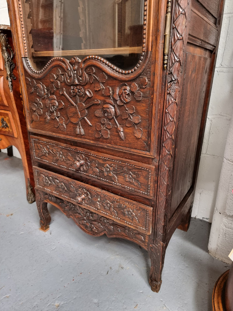 Petite oak armoire display cabinet with a glass door, two drawers at the bottom and three shelves inside. Late 18th Century and amazing detailed decorative carvings. Sourced from France and in good original condition.