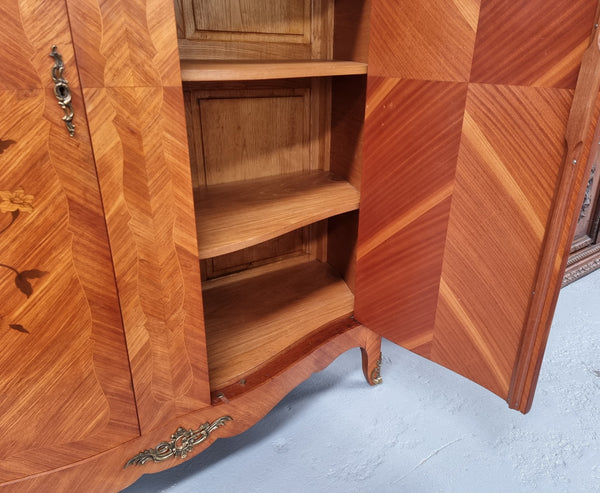 Charming French Louis XV Style Marquetry Inlaid Two Door Armoire. Features three adjustable shelves and ormolu trim. It has been sourced from France and is in good original condition.