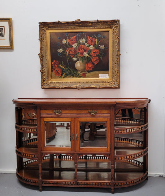 A high quality Antique Walnut sideboard featuring two mirrored doors, two drawers and five open shelf areas with mirror backing. It is in good original detailed condition.
