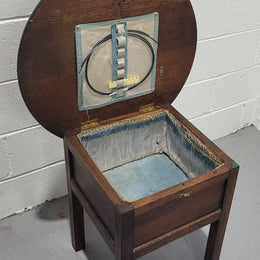 Fabulous round oak side table which also has a hidden sewing box underneath with lovely original blue satin lining and Includes pictured sewing items. It is in good original condition.