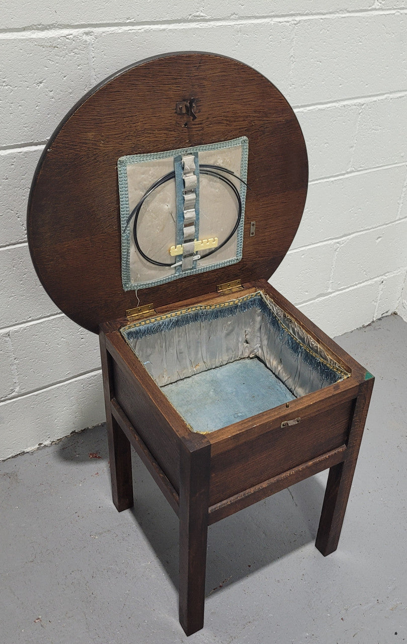 Fabulous round oak side table which also has a hidden sewing box underneath with lovely original blue satin lining and Includes pictured sewing items. It is in good original condition.